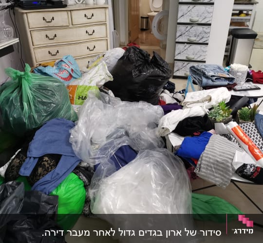 בגדים ופריטים מפוזרים על שולחן ושקיות פלסטיק